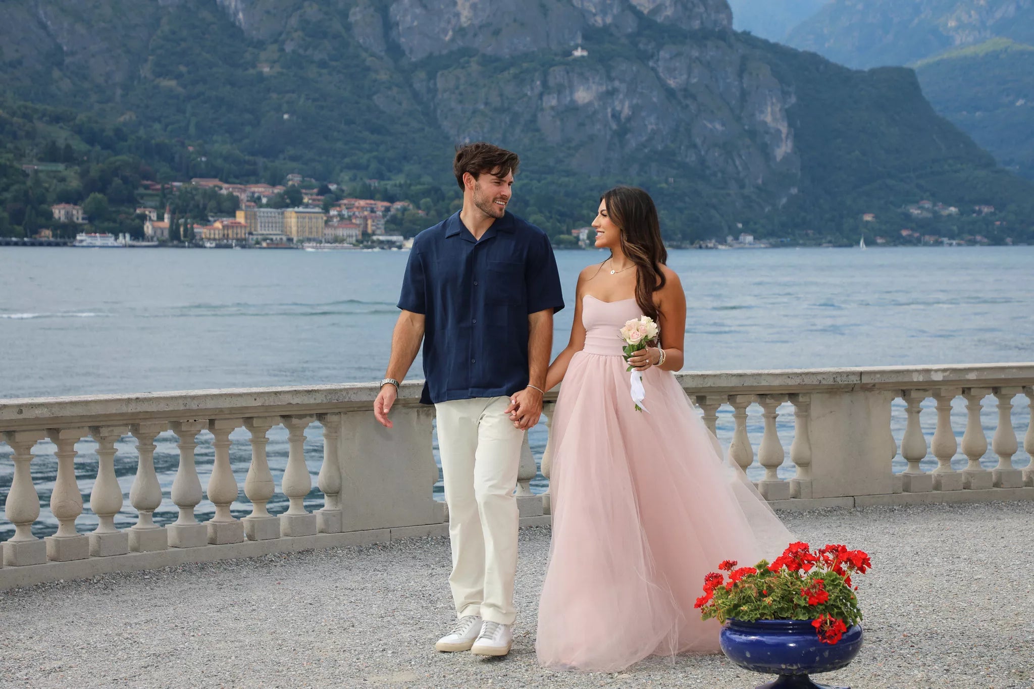 Engaged couple walking along the Bellagio lakeside promenade during a golden hour Lake Como proposal photo shoot