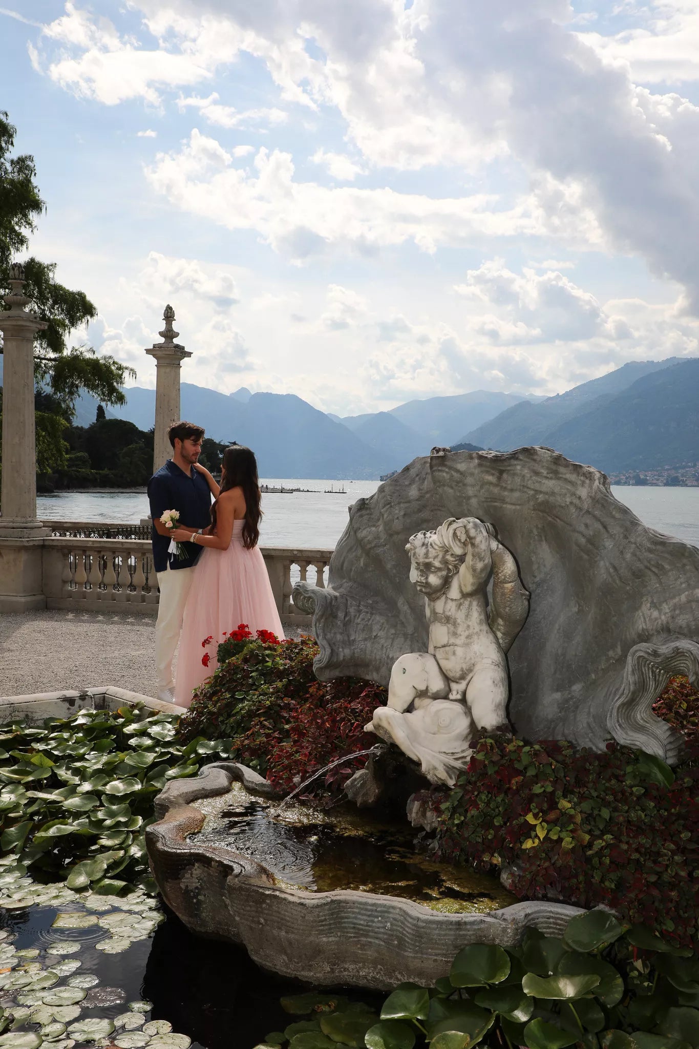 Romantic moment by the ornate fountain and lily pond at Villa Melzi with Lake Como in the distance