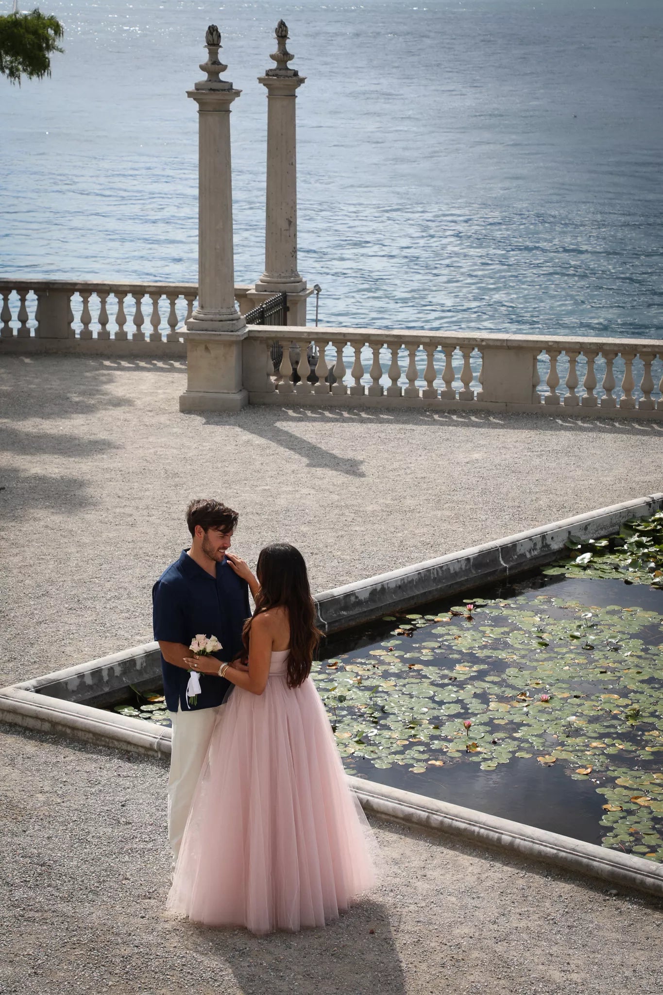 Overhead view of a couple standing by the lily pond and stone balustrade at Villa Melzi during a Bellagio engagement shoot