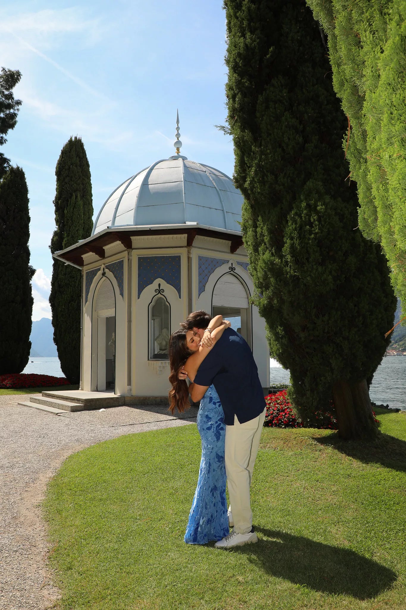 Couple embracing after a surprise proposal beside the lakeside pavilion at Villa Melzi gardens in Bellagio