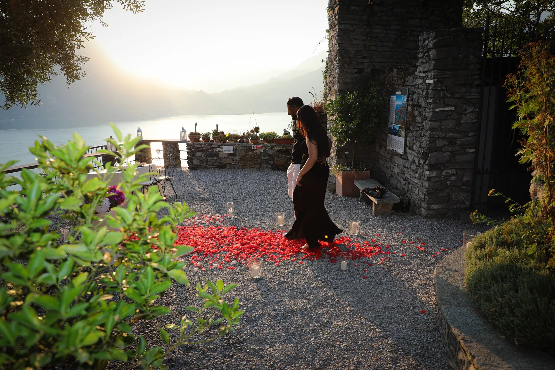 Couple walking through a romantic flower proposal setup at Castello di Vezio during sunset on Lake Como