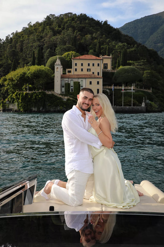 Engaged couple posing on the back of a wooden boat after a Lake Como proposal