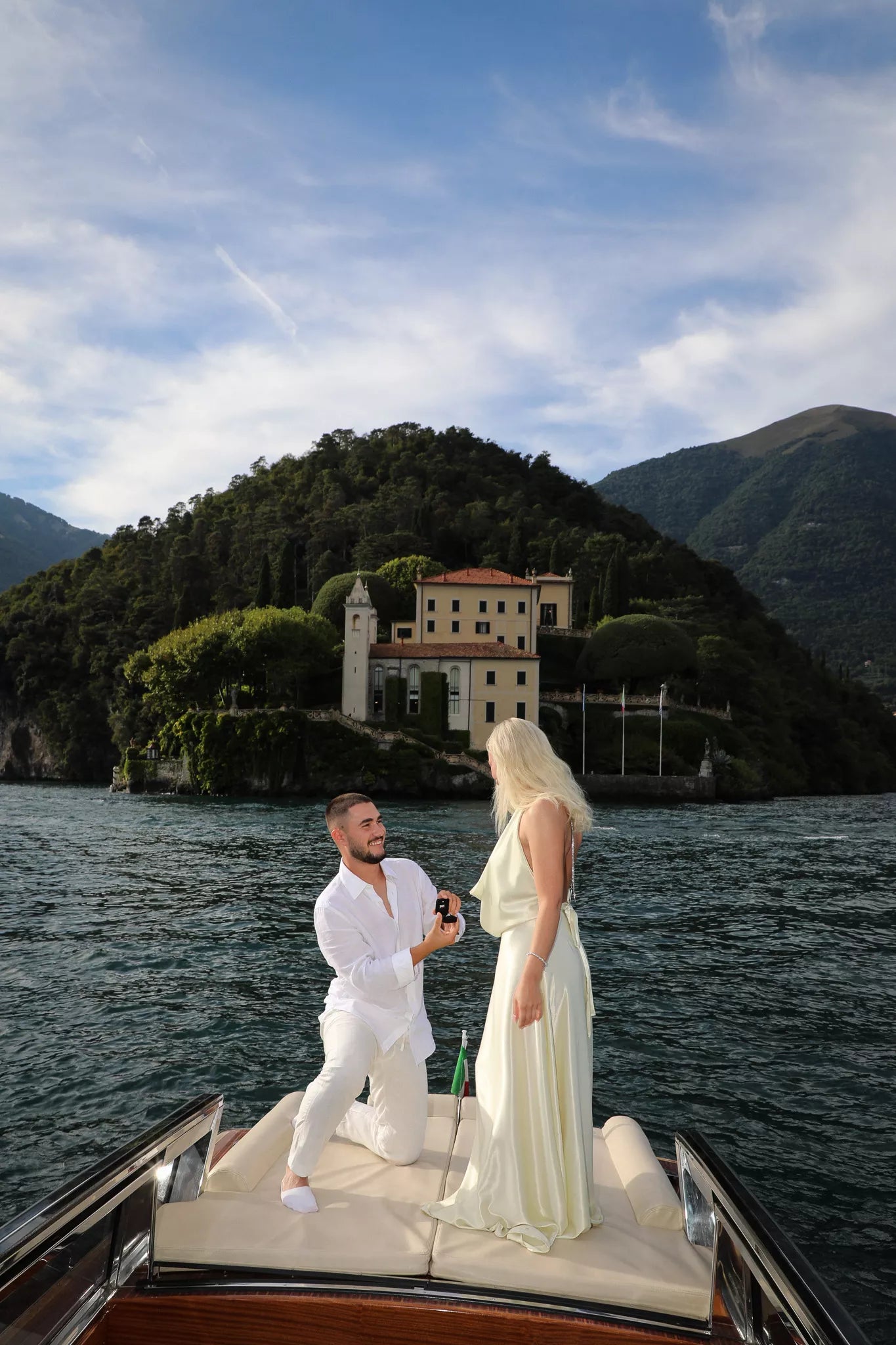 Man proposing on a private boat in front of a lakeside villa on Lake Como