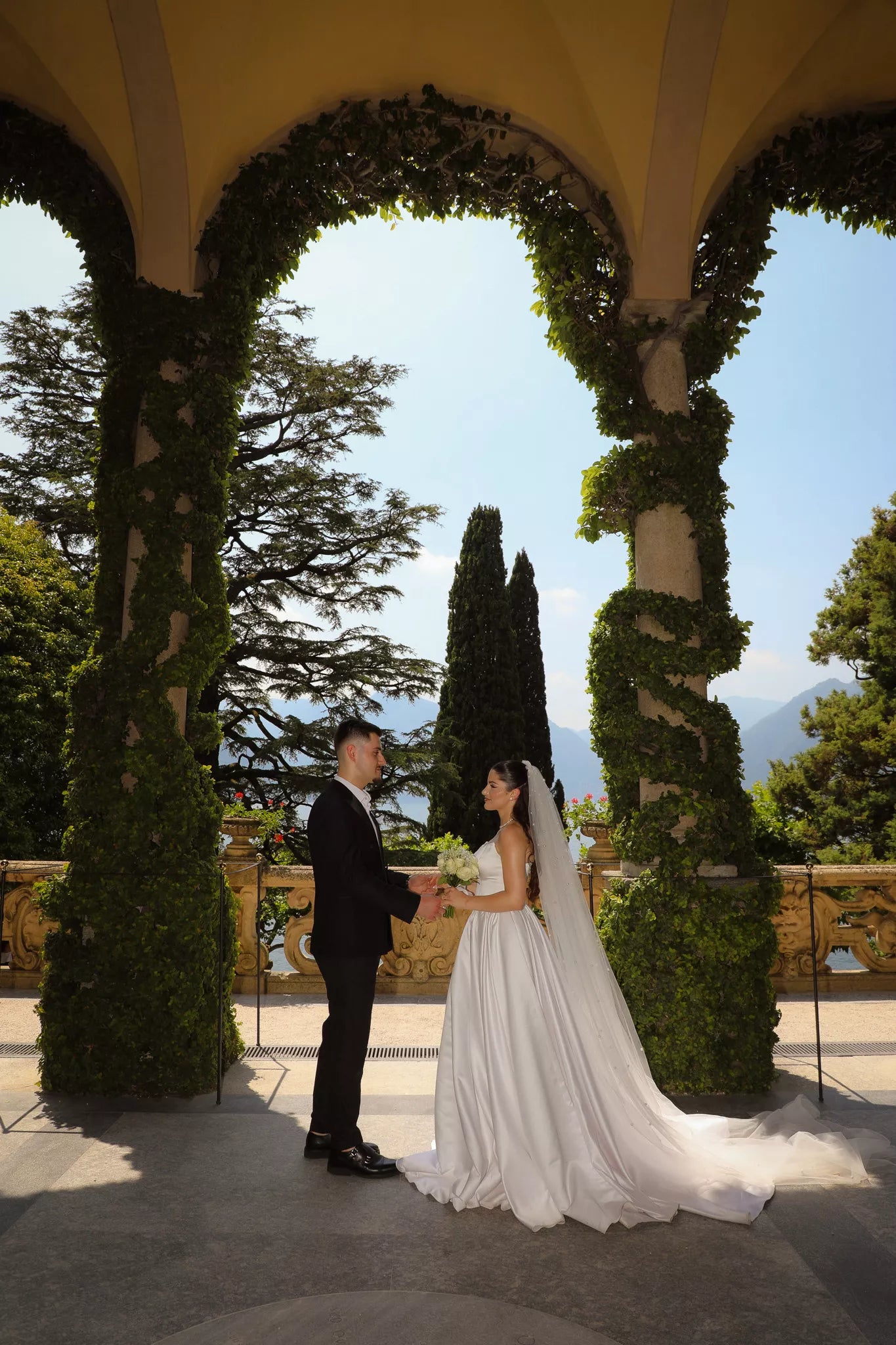 Lake Como wedding photographer capturing bride and groom kissing beneath the Villa del Balbianello loggia
