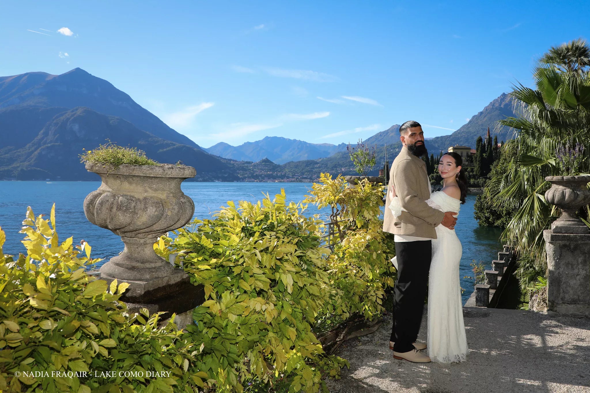 Engaged couple walking along the Varenna lakeside promenade during a golden hour Lake Como proposal photo shoot