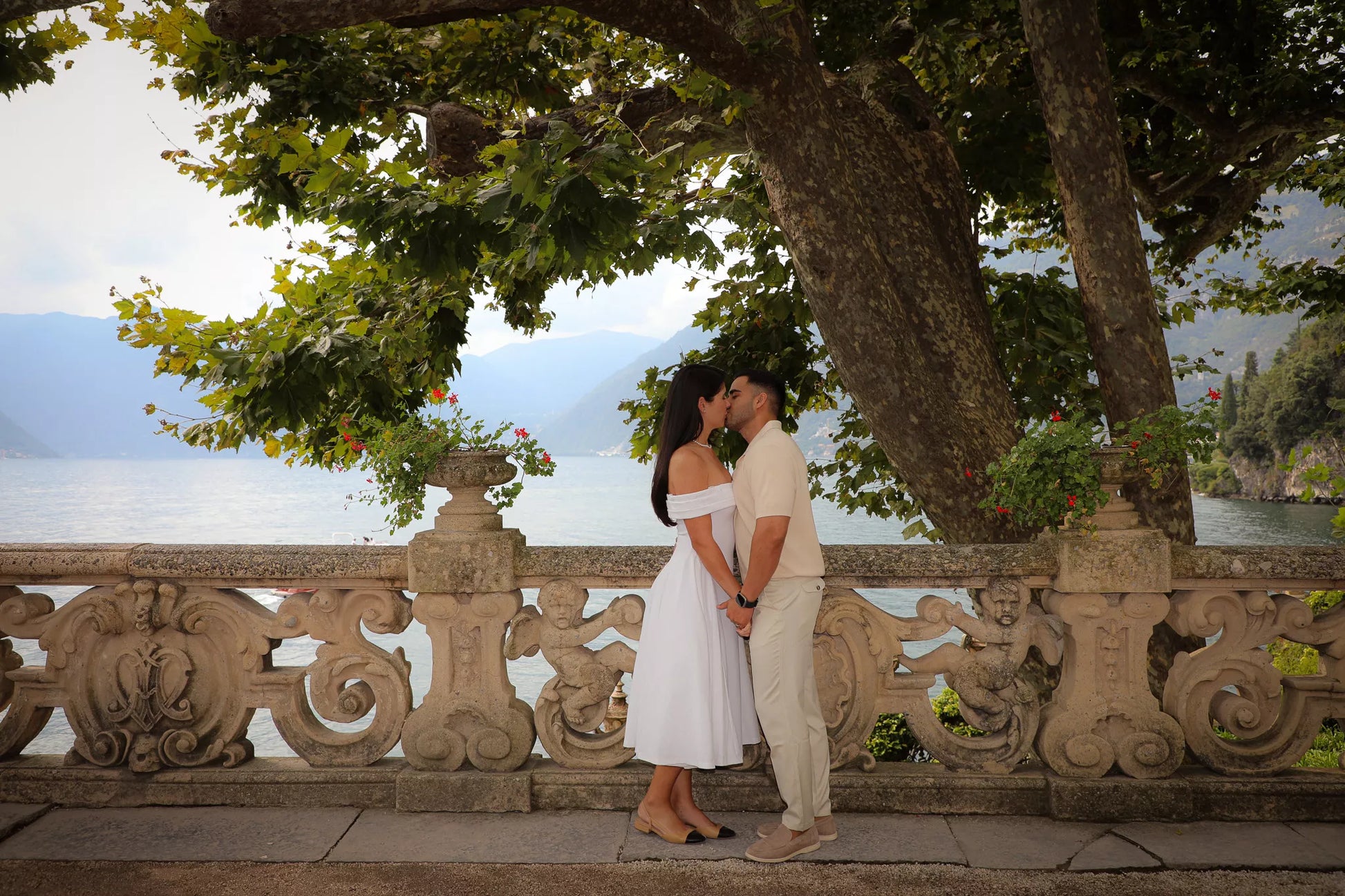Romantic engagement kiss at Villa del Balbianello terrace overlooking Lake Como
