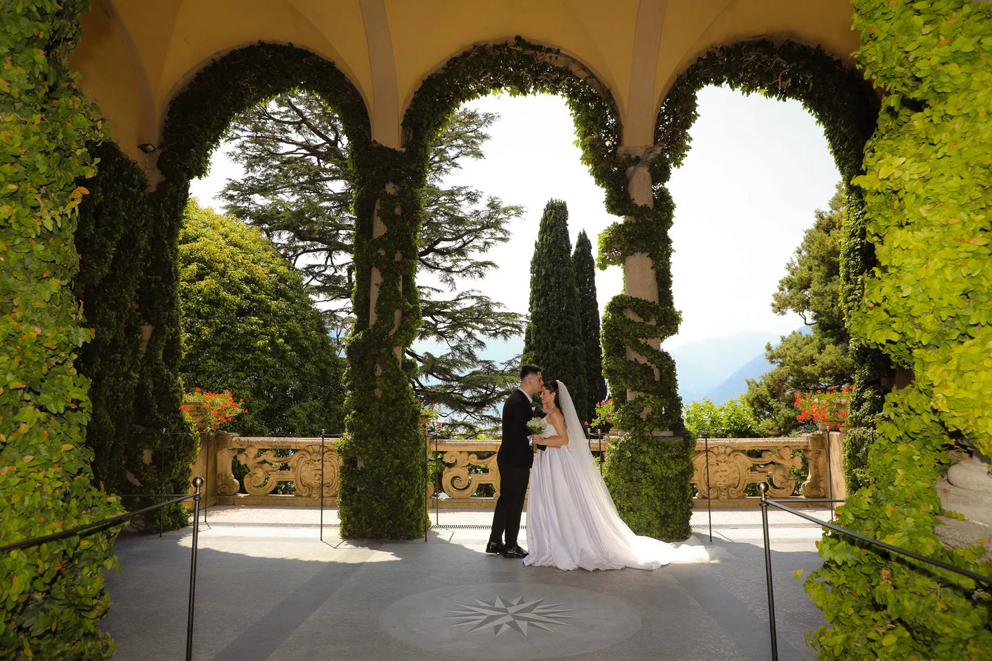 Bride and groom sharing a kiss beneath the ivy-covered loggia at Villa del Balbianello during a Lake Como wedding