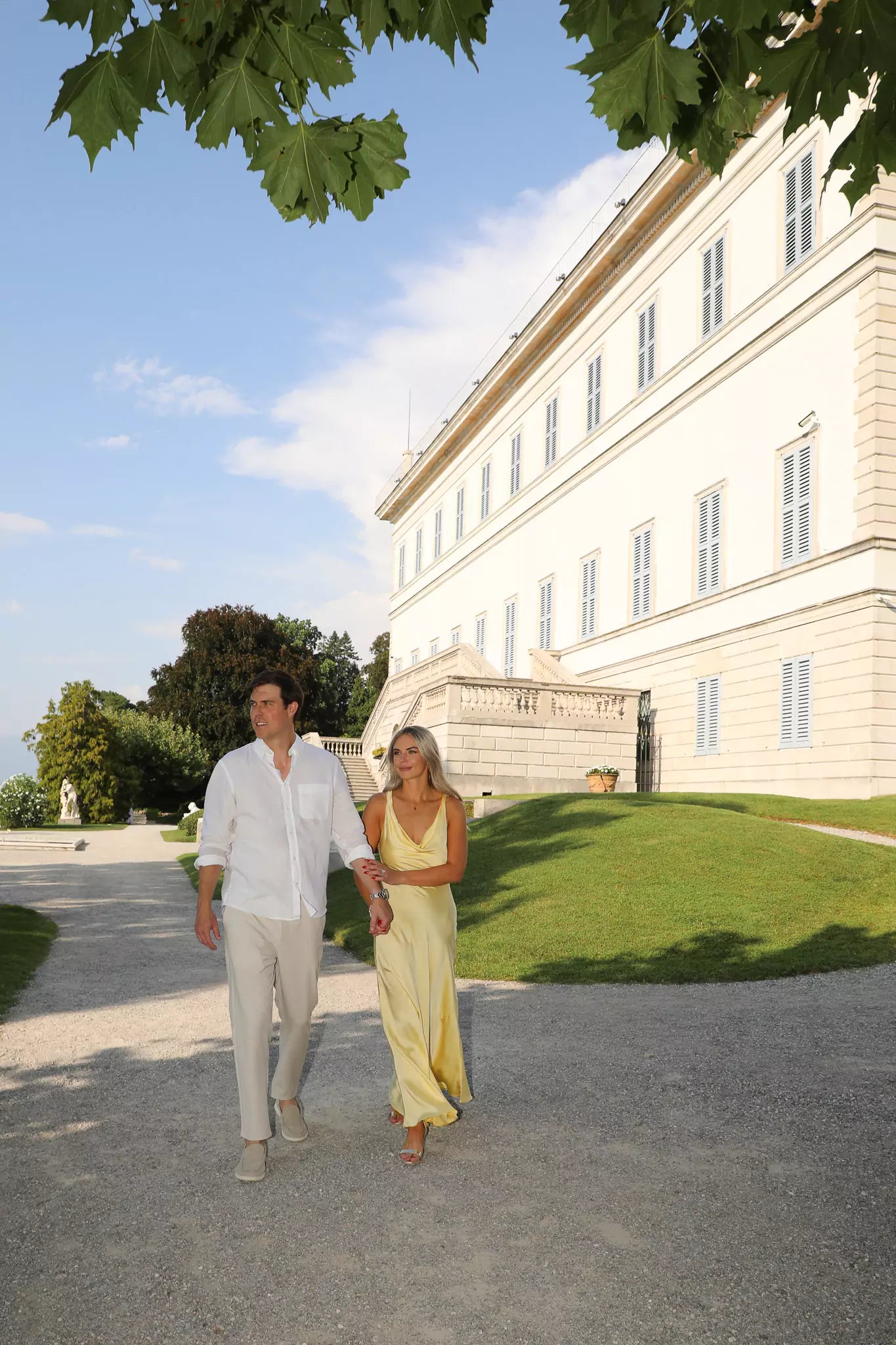 Couple walking through the lakeside gardens of Villa Melzi in Bellagio, Lake Como during a proposal.